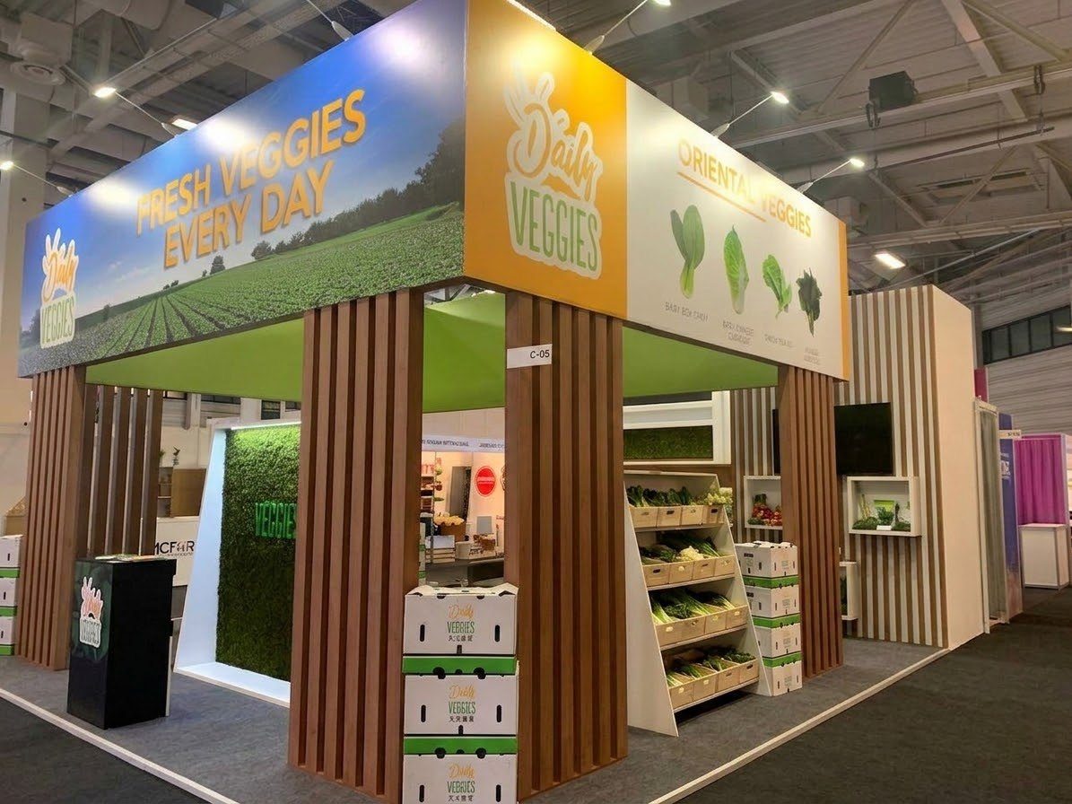 Stand de Daily Veggies en feria con vegetales asiáticos en exhibición